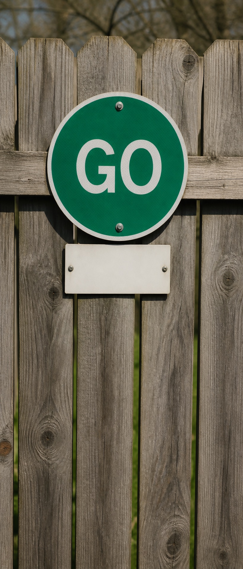 Green go sign on a wooden fence.